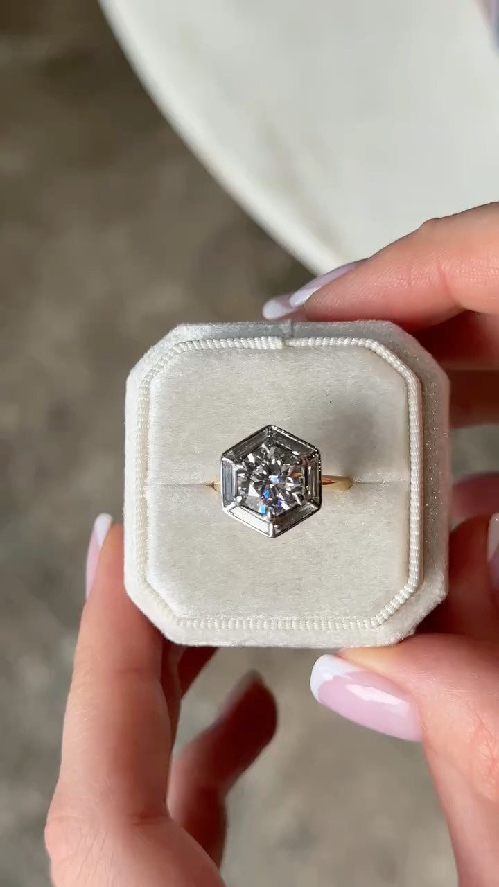 Gold engagement ring with a hexagonal diamond halo setting in a white box
