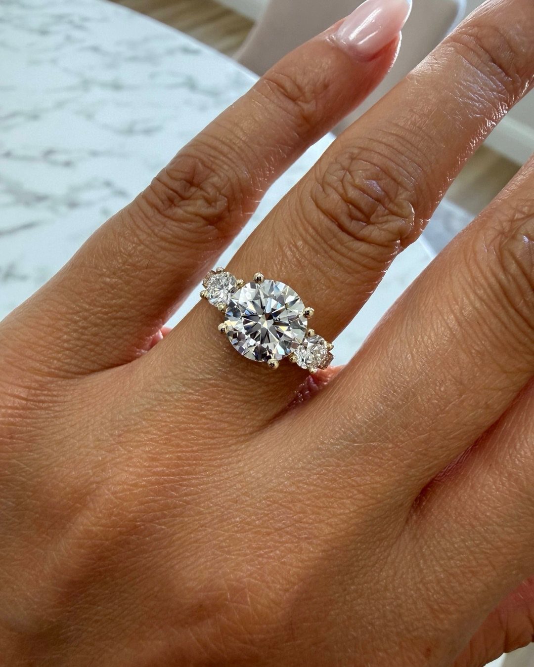 Three-stone engagement ring with round diamonds on a woman's finger