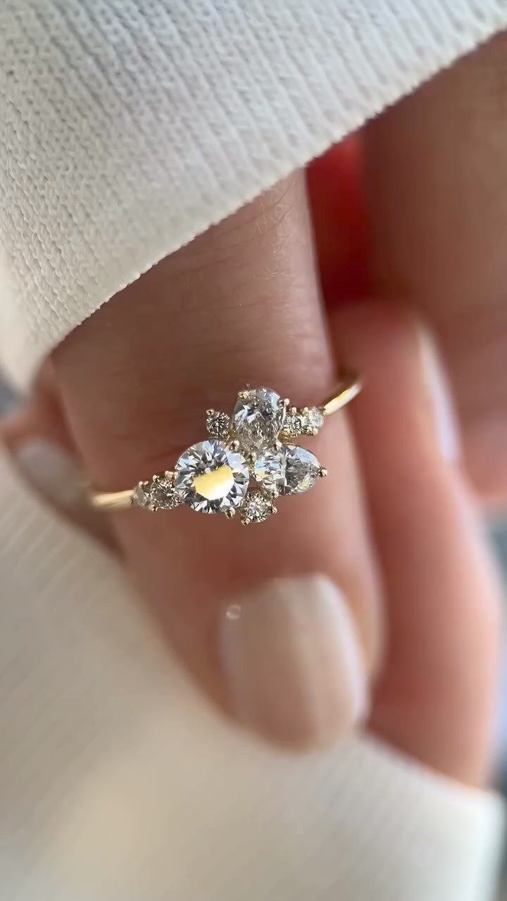 Gold engagement ring with a cluster of diamonds worn on a finger