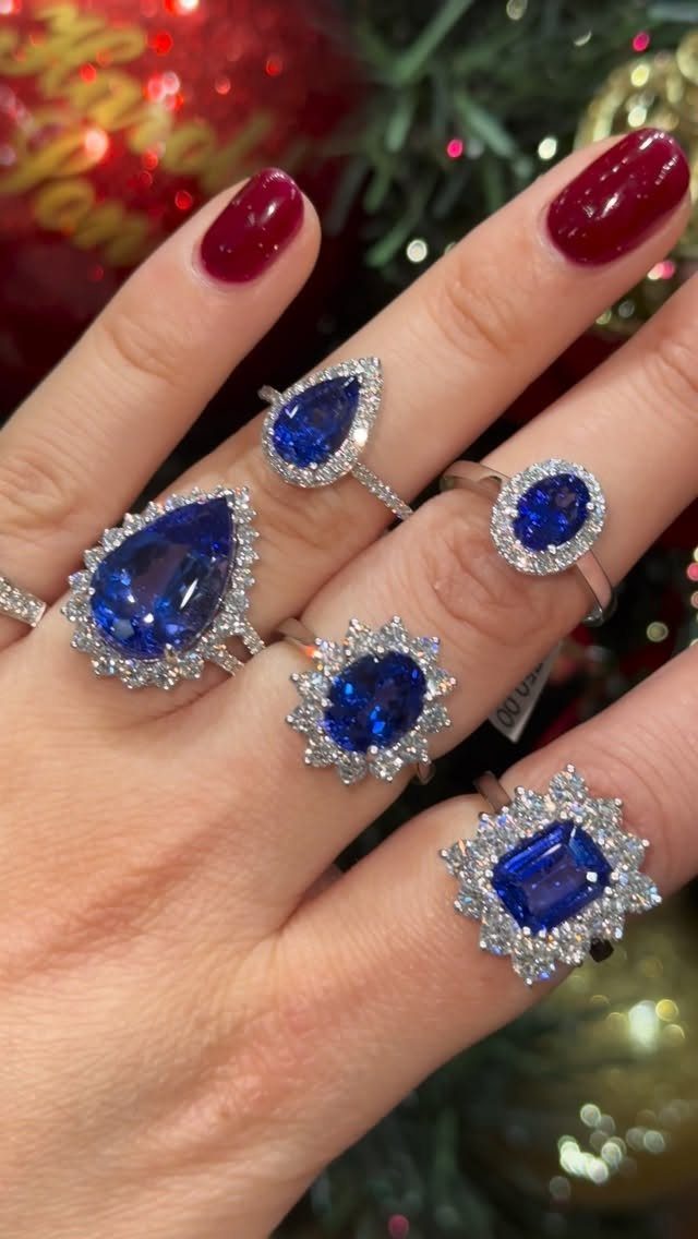 Hand with red nails wearing multiple silver rings with blue gemstones and diamonds