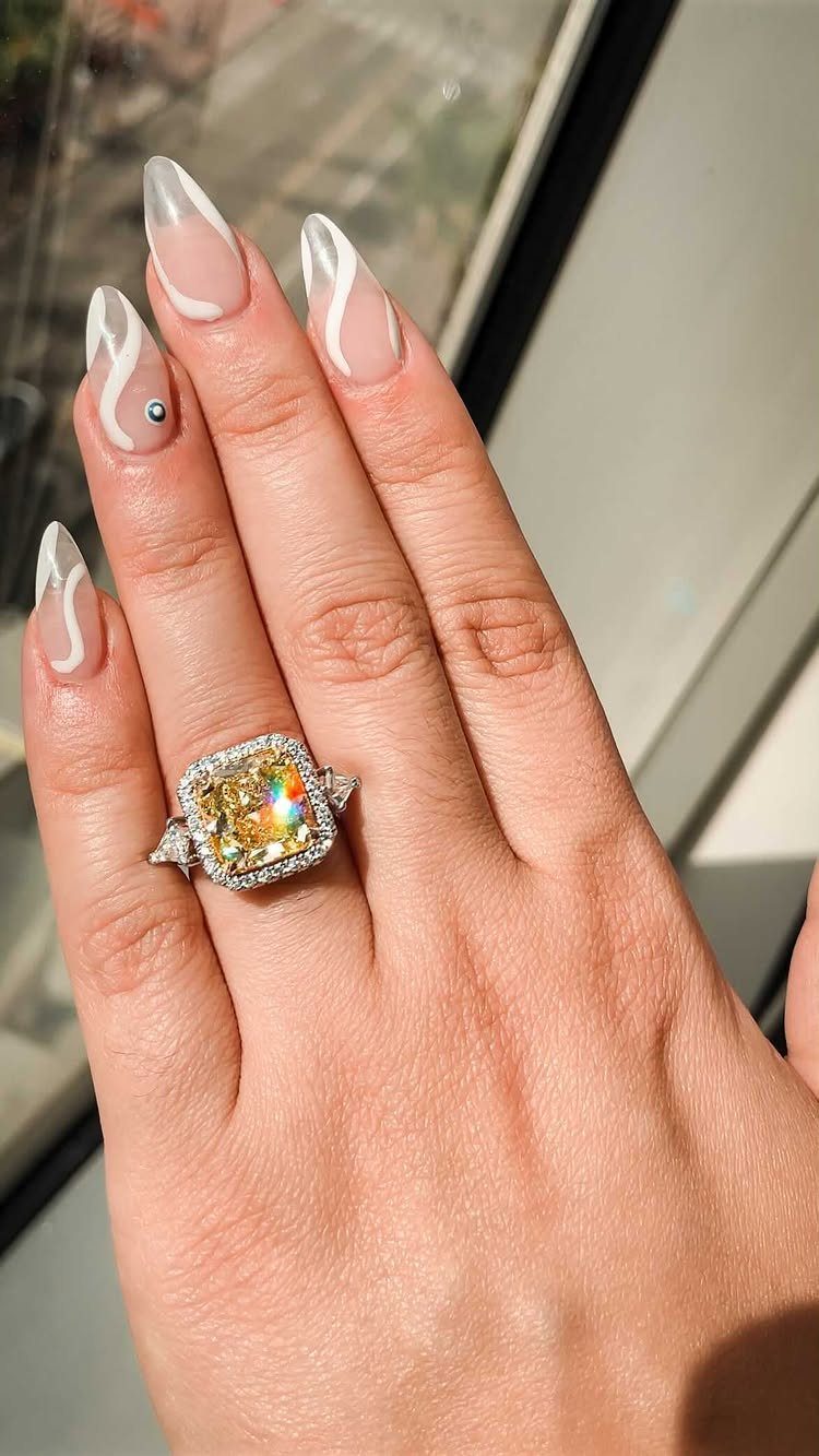 Engagement ring with yellow center stone and diamond halo on a woman's finger