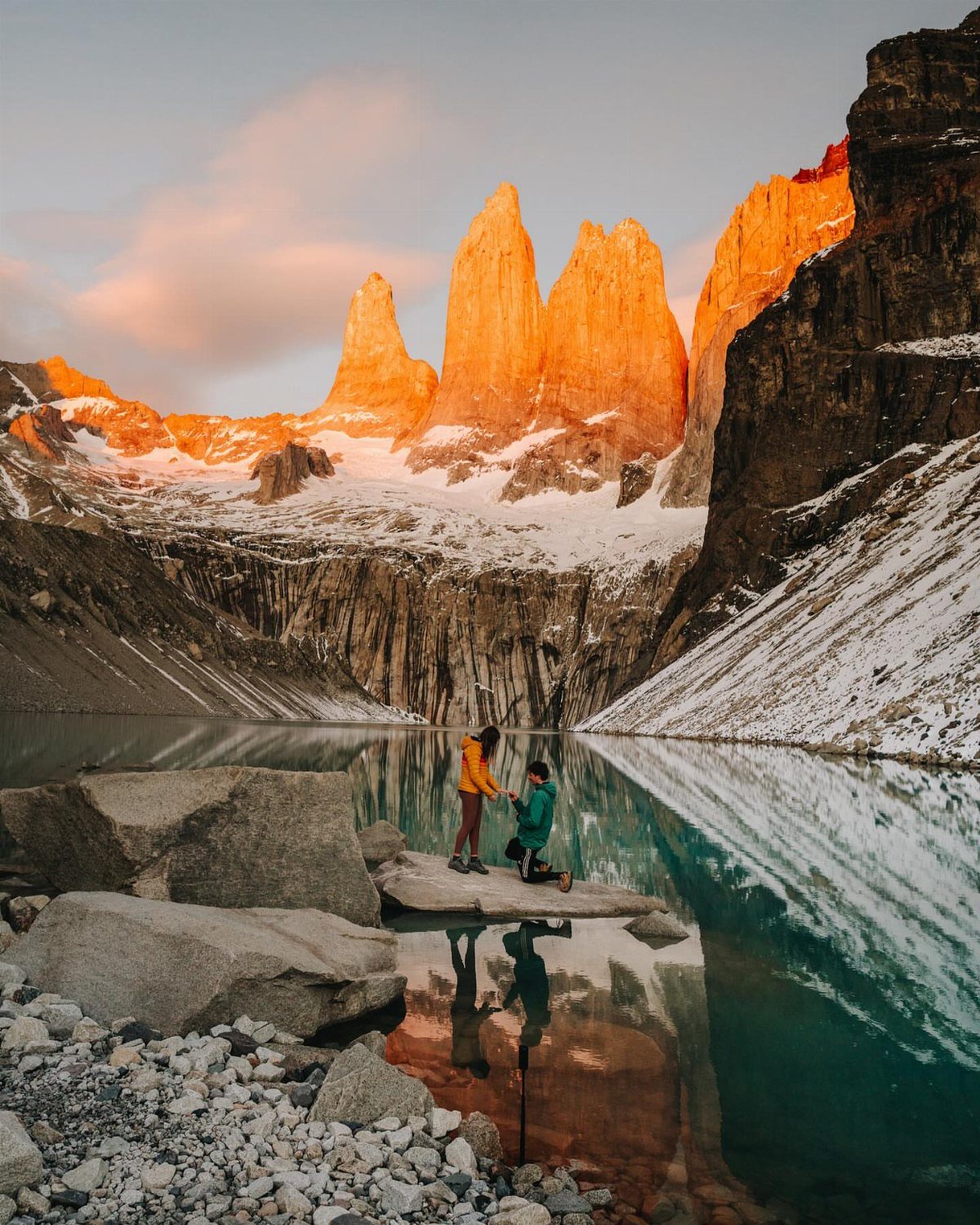 Couple proposing by a turquoise lake with orange granite peaks in Patagonia