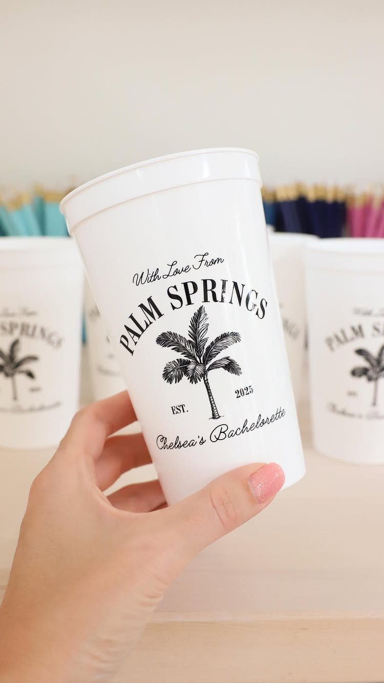 White party cup with Palm Springs and bachelorette text held by a hand.
