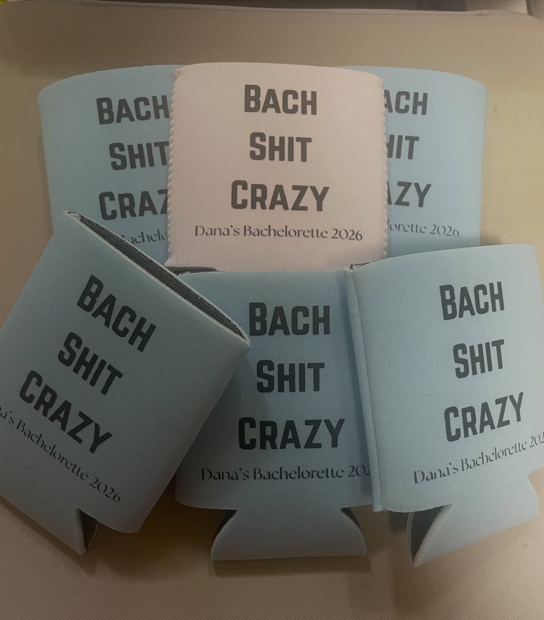 Light blue and white foam drink insulators with bachelorette party text on them.