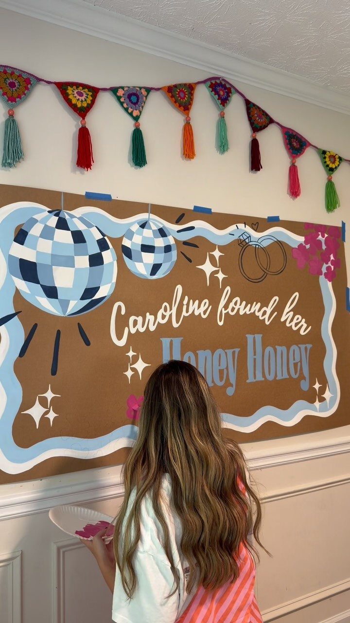 Woman standing in front of a bachelorette backdrop with blue disco ball illustrations.