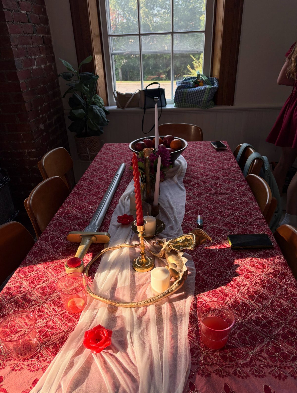 Table setting with red lace, a gold crown, sword, and red roses.