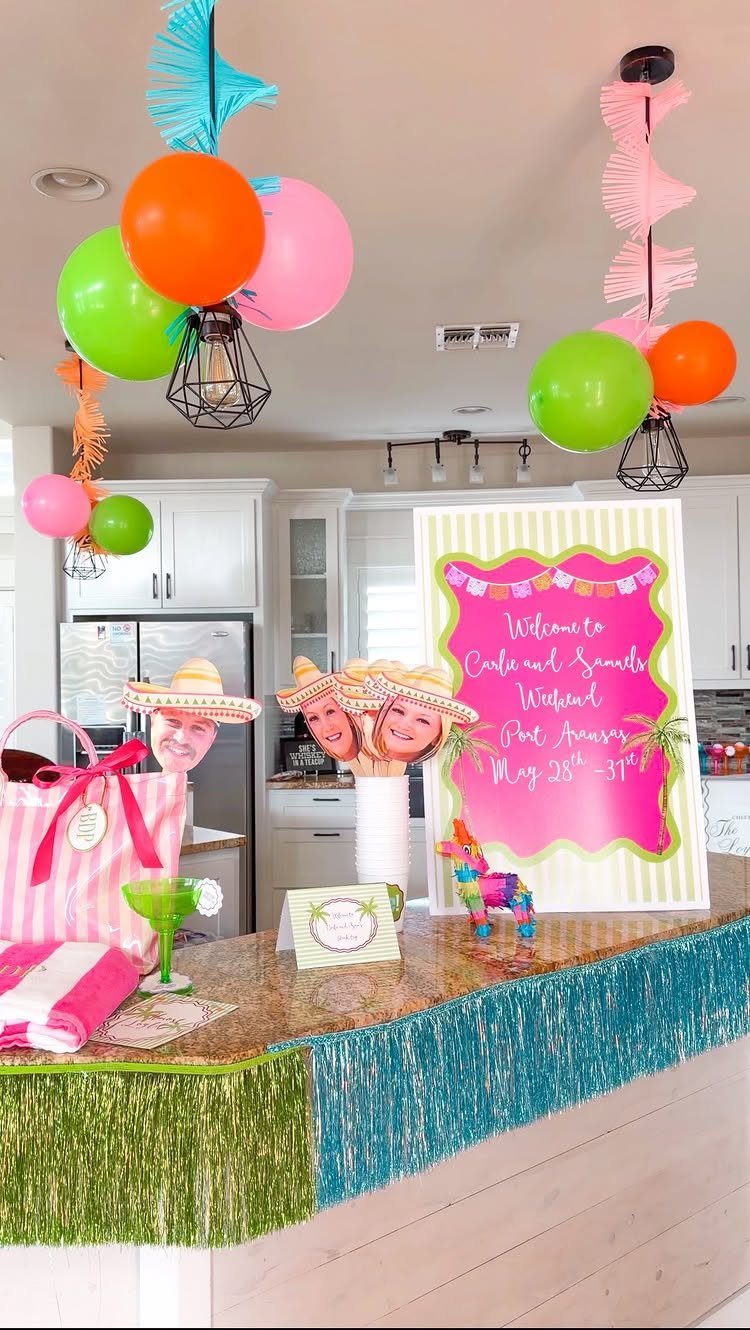 Festive party setup with colorful balloons, sombreros, and a welcome sign on a counter.