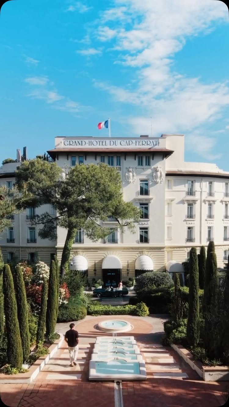 Grand-Hotel du Cap-Ferrat with a tiered fountain and cypress trees in the foreground.