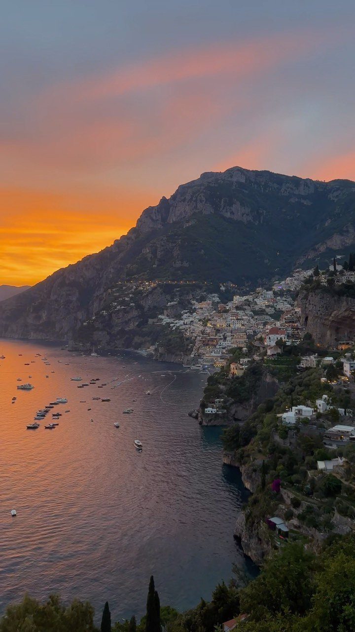 Coastal town with white buildings on a cliffside during a vibrant sunset.