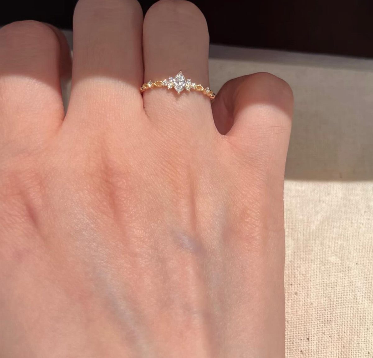 Gold engagement ring with marquise diamond worn on a person's ring finger