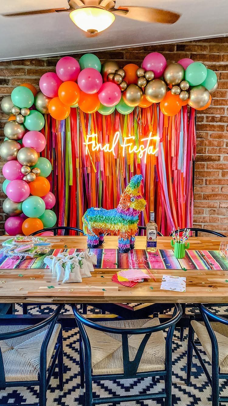 Colorful party decorations with a Final Fiesta neon sign and piñata unicorn