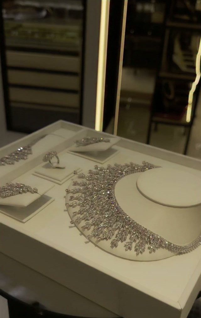 Diamond bridal jewelry set including a necklace, earrings, and ring on white displays.