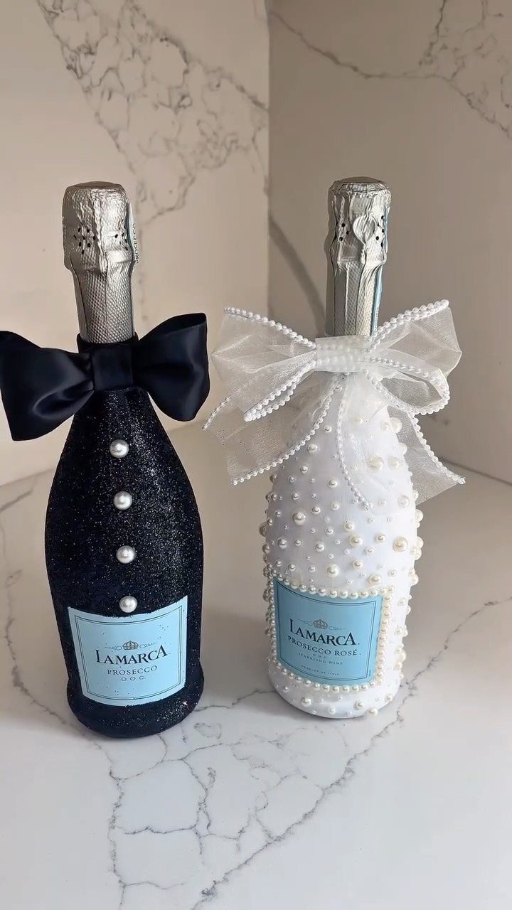 Two decorated champagne bottles, one black and one white, adorned with pearls and bows.