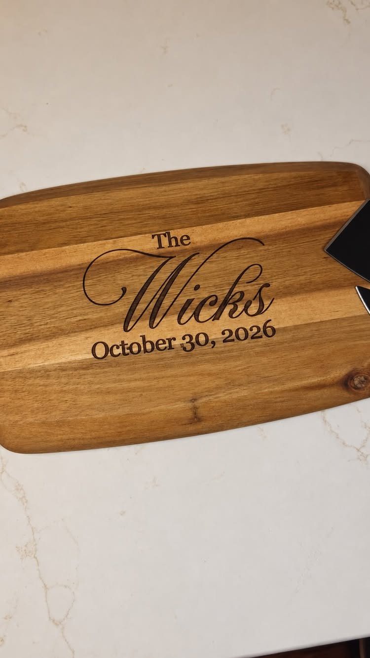 Wooden cutting board engraved with The Wicks and a wedding date on marble.