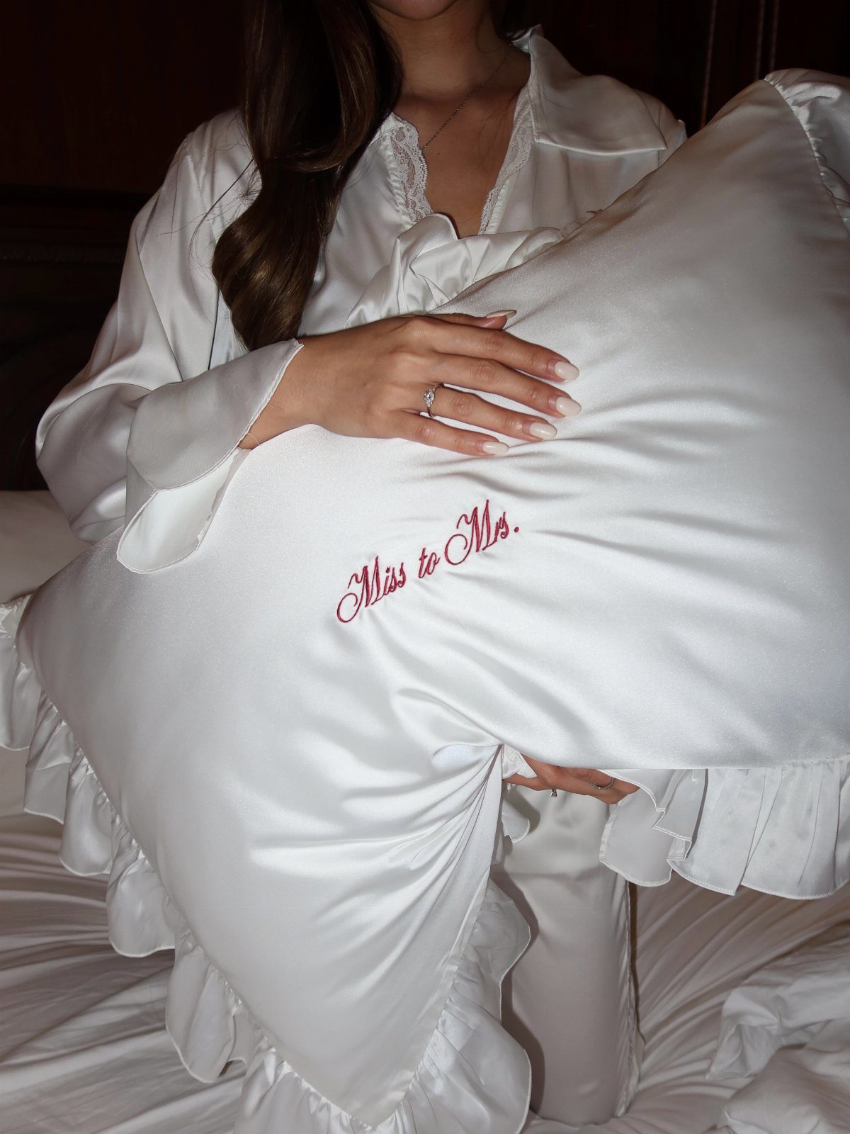 White satin pillow with red Miss to Mrs embroidery held by a woman