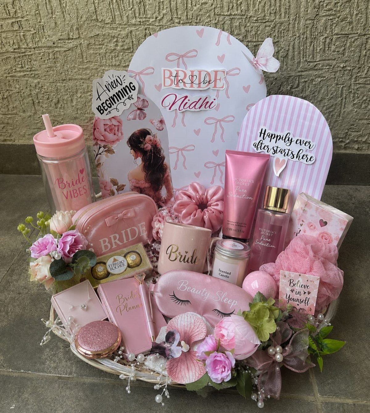Pink bridal gift basket with skincare, a sleep mask, and bride-themed accessories.