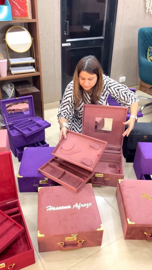 Woman displaying large red and purple velvet jewelry cases with organized compartments.