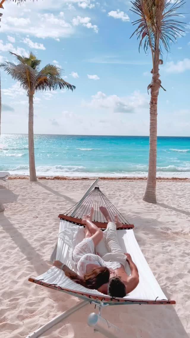 Couple cuddling in a white hammock on a tropical beach with turquoise water.
