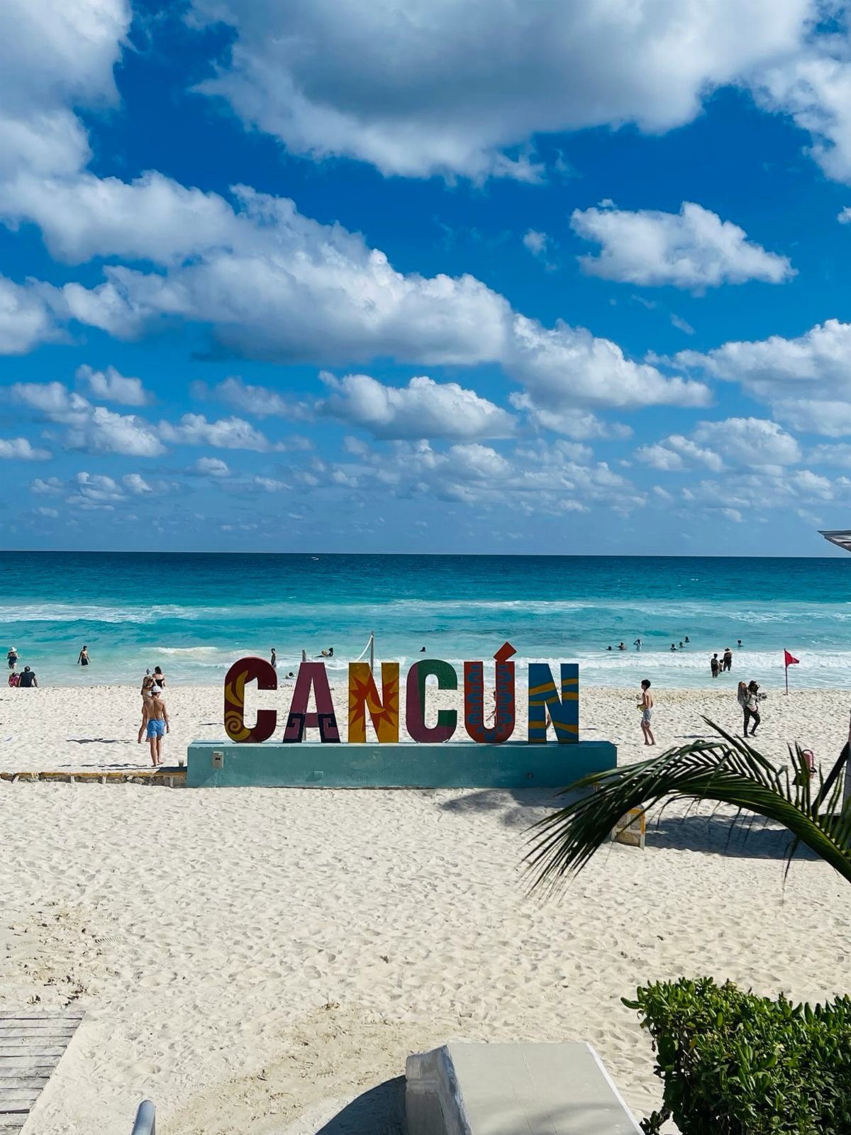 Colorful CANCÚN sign on a white sandy beach with turquoise ocean water.