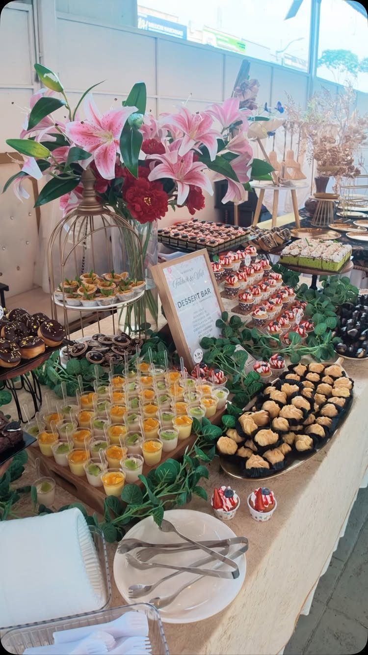 Dessert bar with mini parfaits, donuts, and pastries decorated with pink lilies.