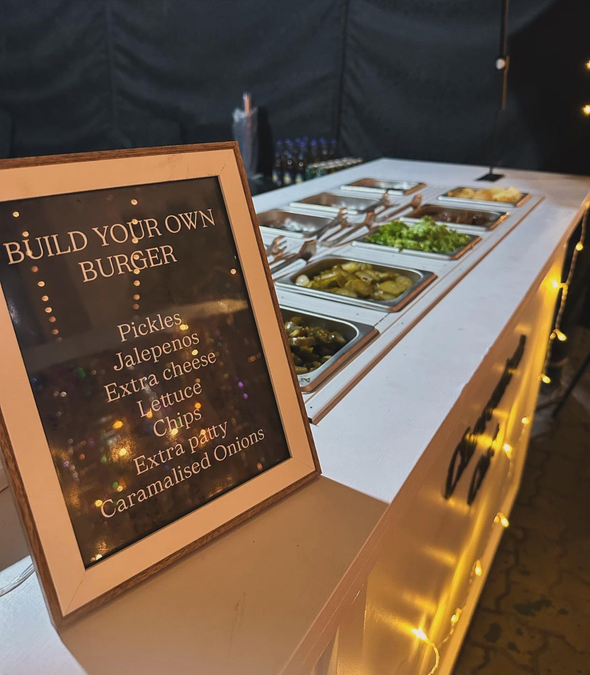 Build Your Own Burger station with topping trays and a framed menu sign.