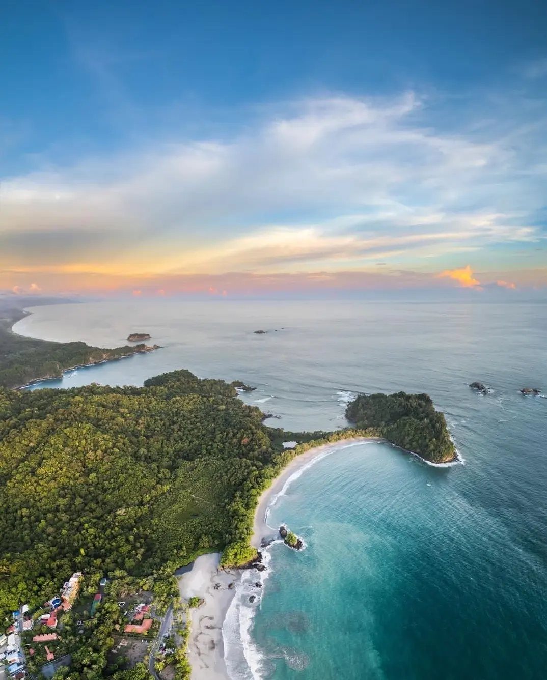 Tropical coastline with white sand beach, turquoise water, and lush green jungle forest.