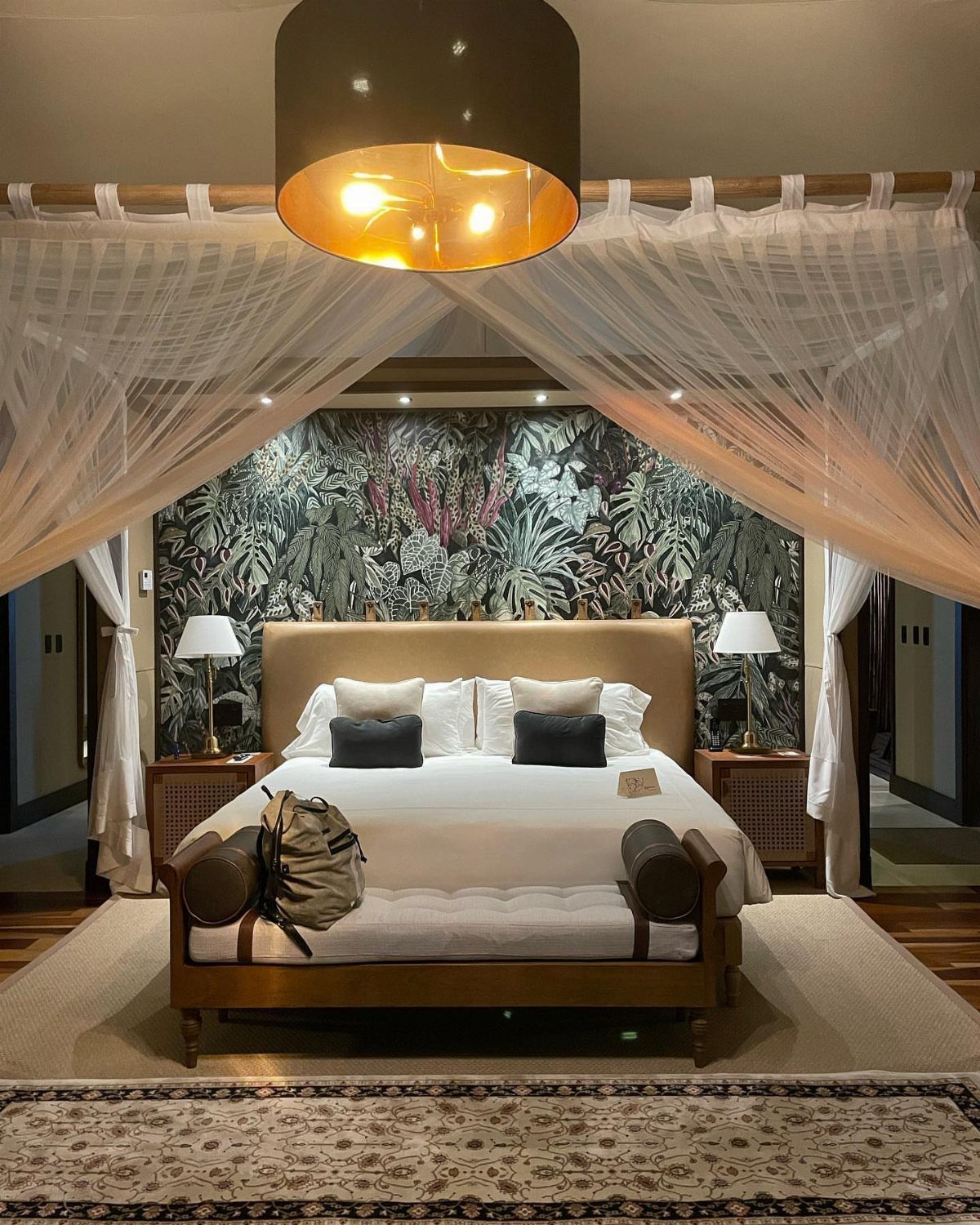 Luxurious bedroom with a canopy bed and tropical leaf wallpaper in a resort.