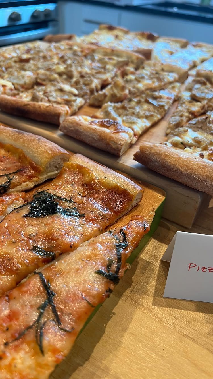 Pizza slices on wooden boards and a platter with a small label.