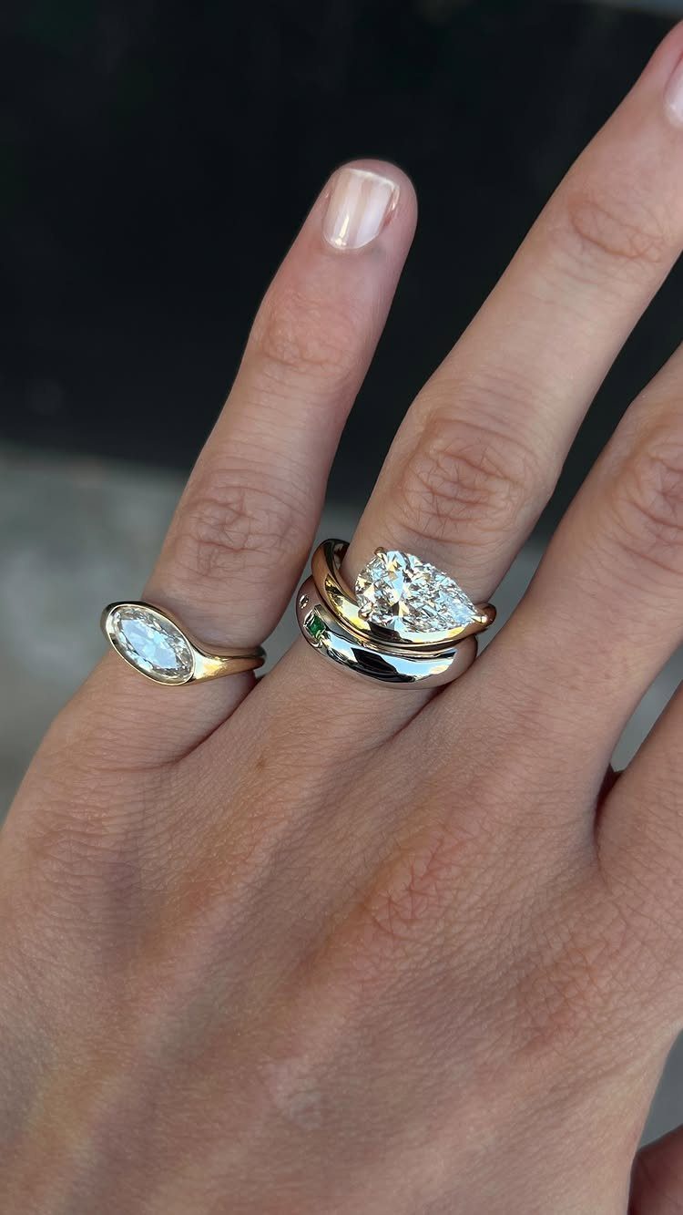 Hand wearing rose gold and white gold rings with pear and marquise diamonds.