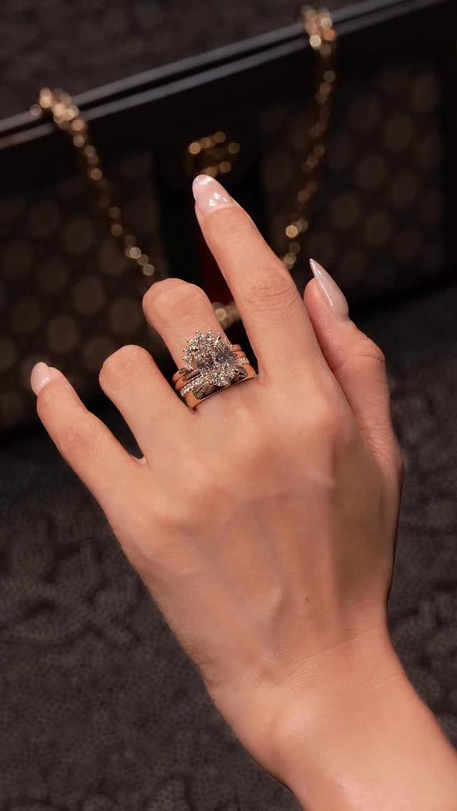 Stacked rose gold diamond rings on a finger against a designer handbag background