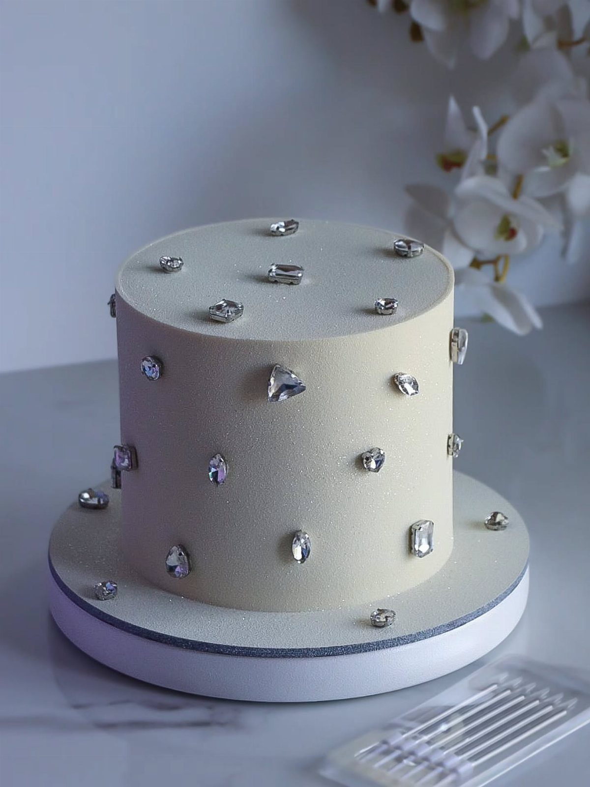 White fondant cake decorated with scattered clear crystal shards and rhinestones.