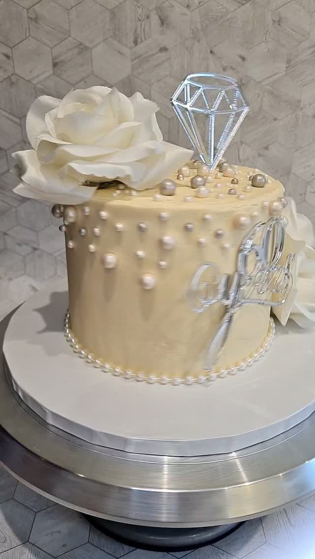 Cream cake with white pearls, a sugar rose, and a diamond topper