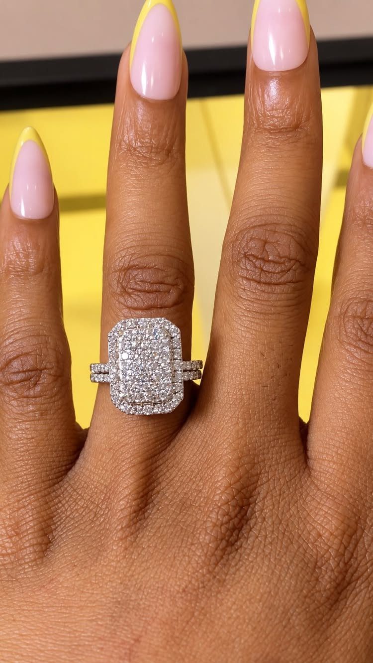 Diamond engagement ring with a rectangular cluster on a hand with yellow-tipped nails.