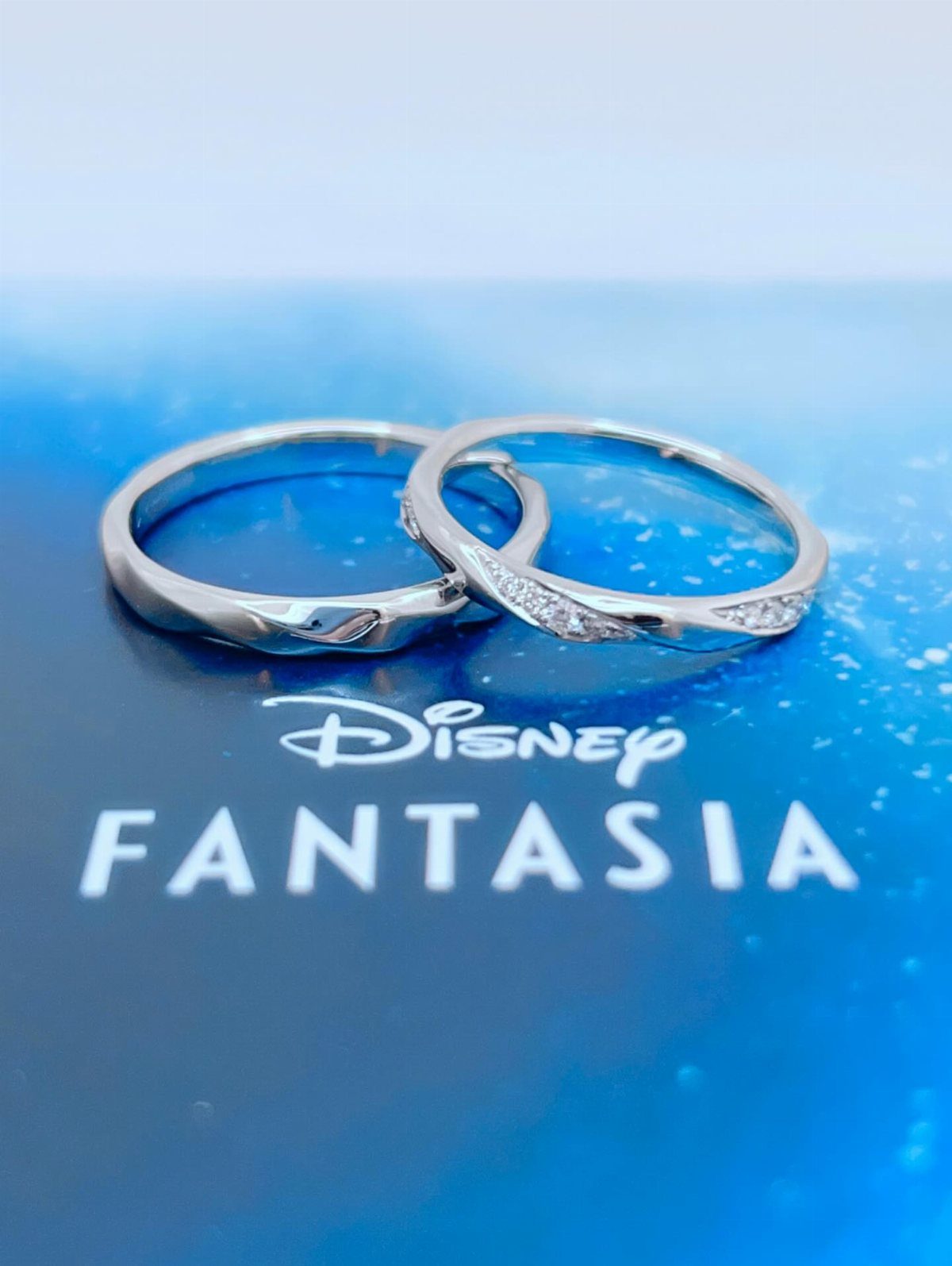 Two silver Disney Fantasia rings resting on a blue branded jewelry box.