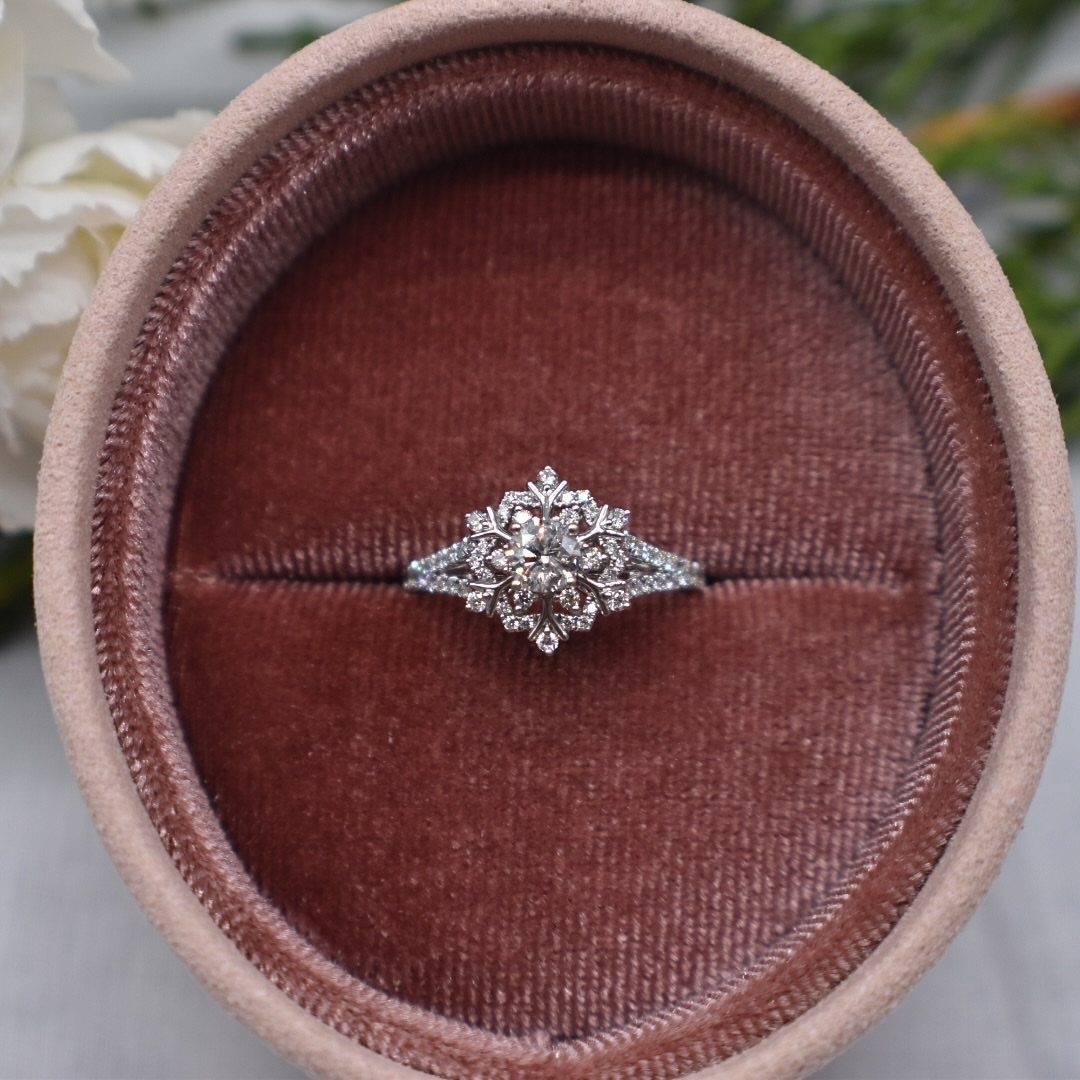 Snowflake-shaped diamond engagement ring resting in a mauve velvet ring box