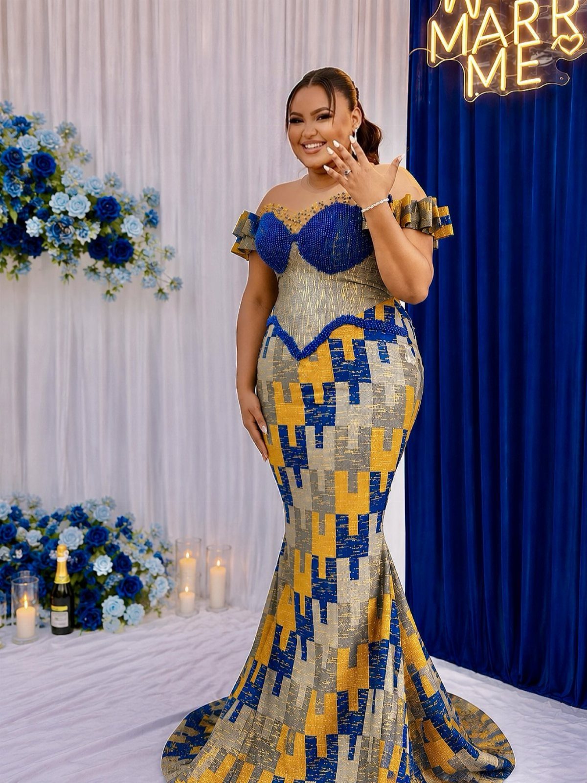 Woman in a blue and yellow patterned mermaid gown posing before blue curtains.