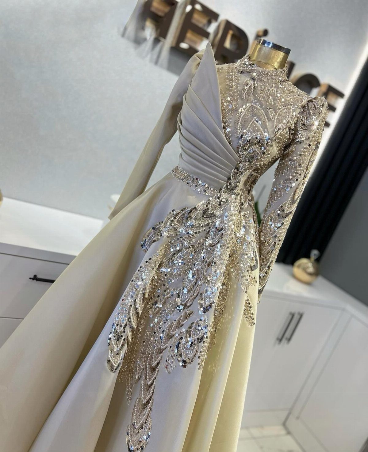 Cream-colored gown on a mannequin with intricate gold and silver sequin embroidery.