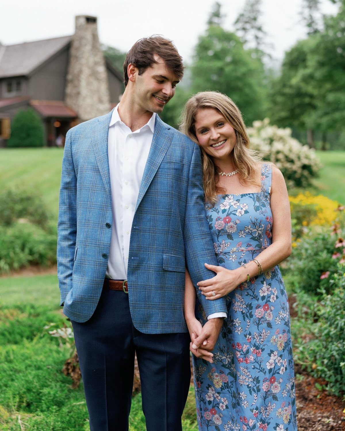 Smiling couple posing outdoors, woman wearing a blue floral midi dress.