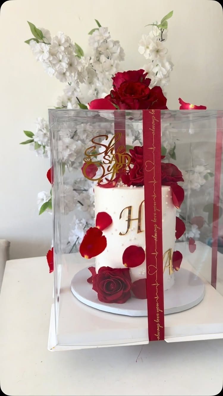 White cake with red roses and a gold She Said Yes topper