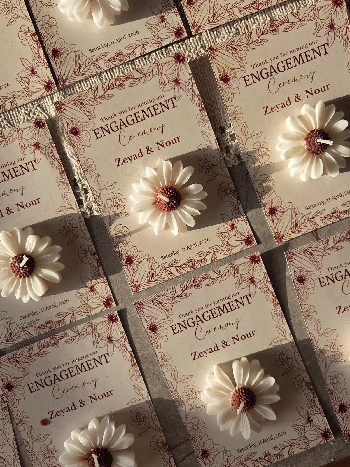 Daisy-shaped white candles on personalized engagement ceremony cards with floral borders.