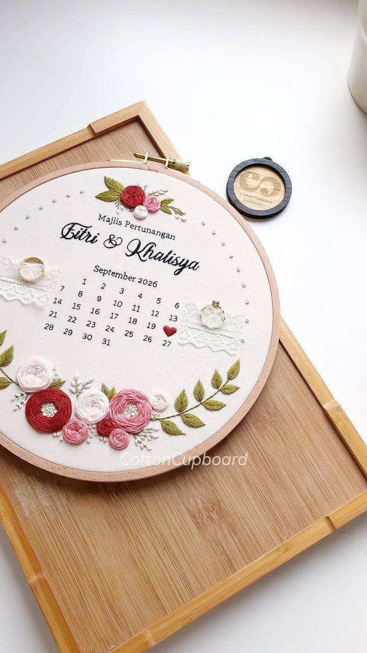 Embroidered hoop art with floral designs and a calendar on a bamboo tray