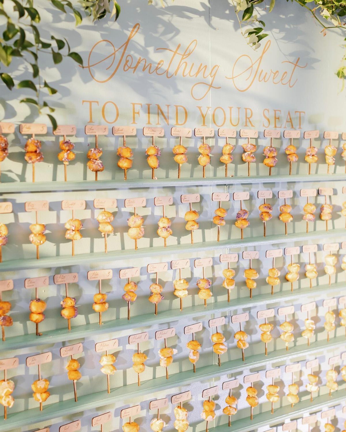 Appetizer skewers with name tags arranged on shelves under a seating chart sign.