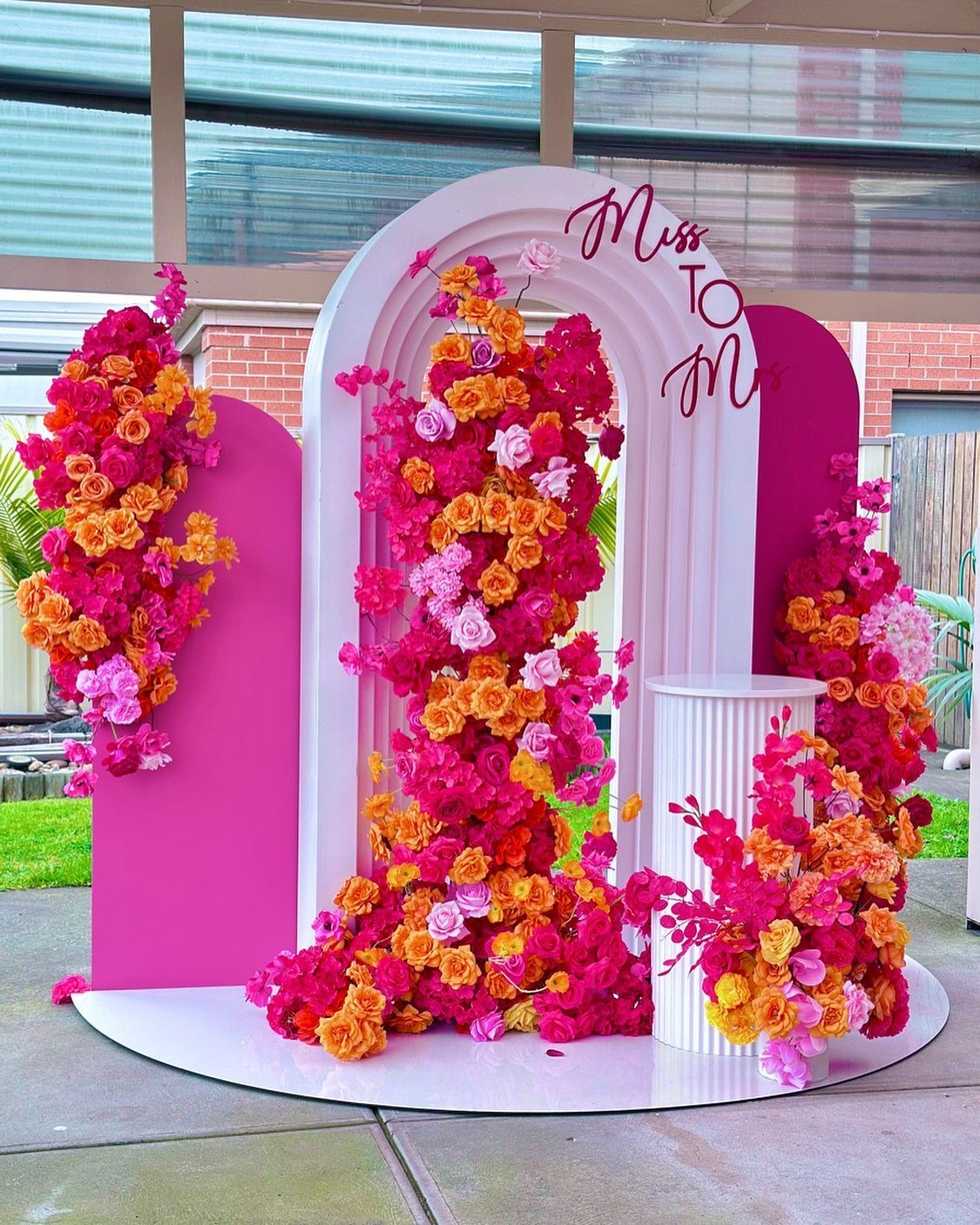 Floral backdrop with pink and orange flowers on white and pink arched panels.