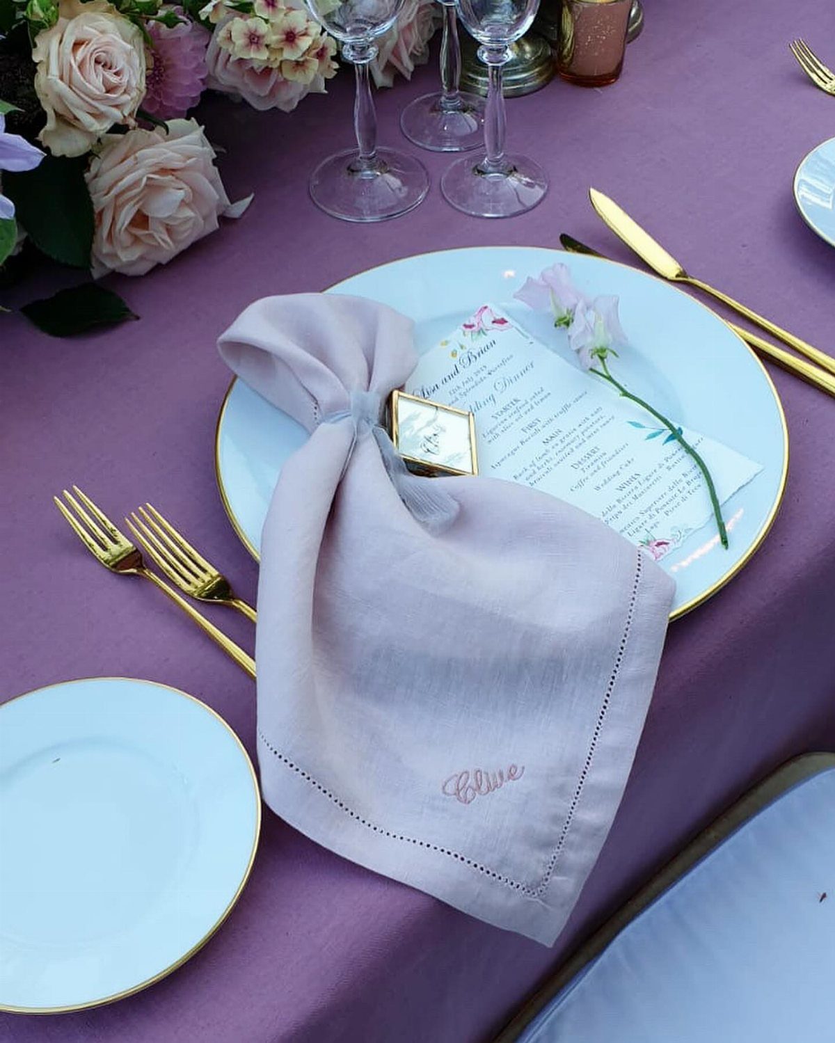 Light purple linen napkin with embroidered name Olive on a purple table setting.
