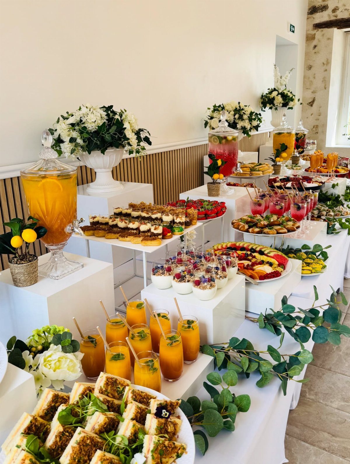 Buffet spread with orange juice, fruit, and sandwiches for a brunch party.