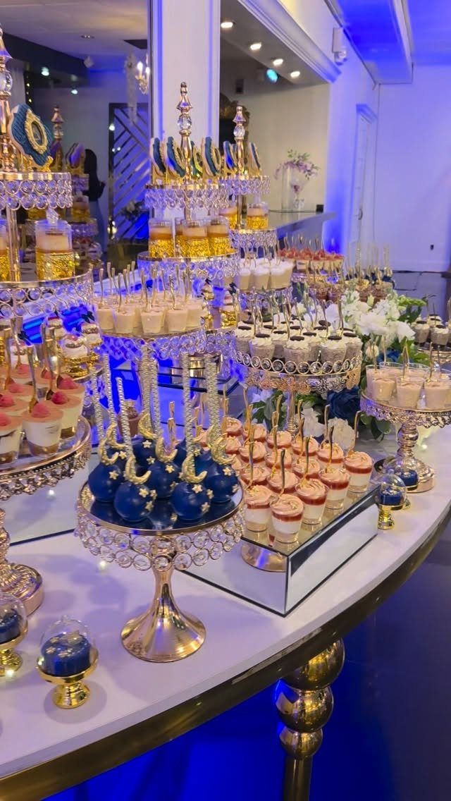 Dessert table with blue and gold treats under blue ambient lighting.