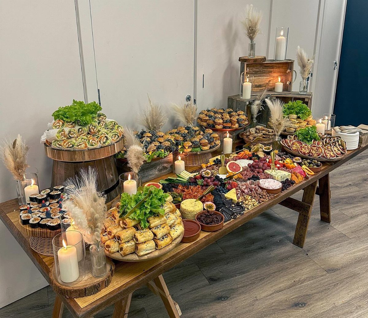 Abundant appetizer spread on a wooden table with candles and pampas grass