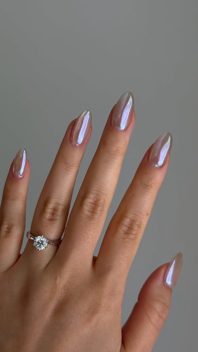 Iridescent glass nails on a hand wearing a diamond engagement ring.