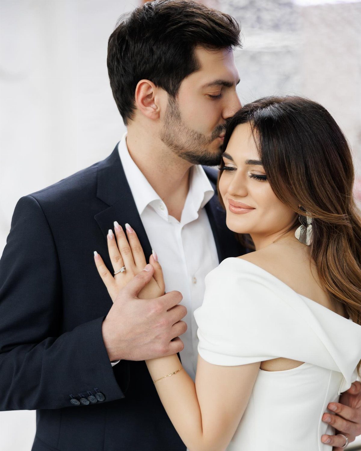 Couple embracing with a focus on the woman's neutral nude nails and engagement ring.