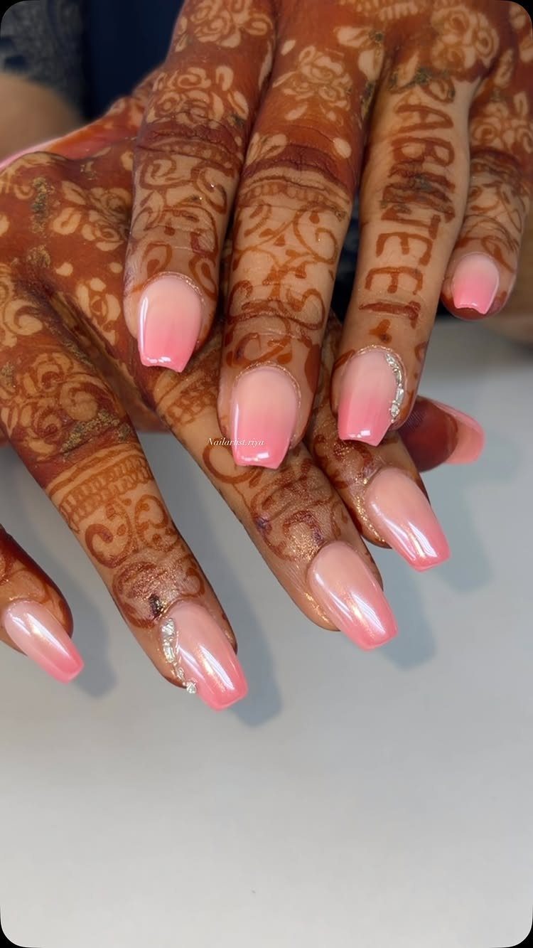 Hands with henna art and pink and white ombre coffin-shaped nails with rhinestones.